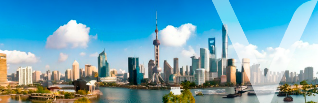 Panoramic view of a modern Chinese city with high-rise buildings, some likely featuring prefab construction techniques, set along a river at sunset.